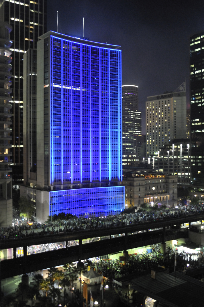 Blue-lit AMP Building with crwods along Cahill Expressway